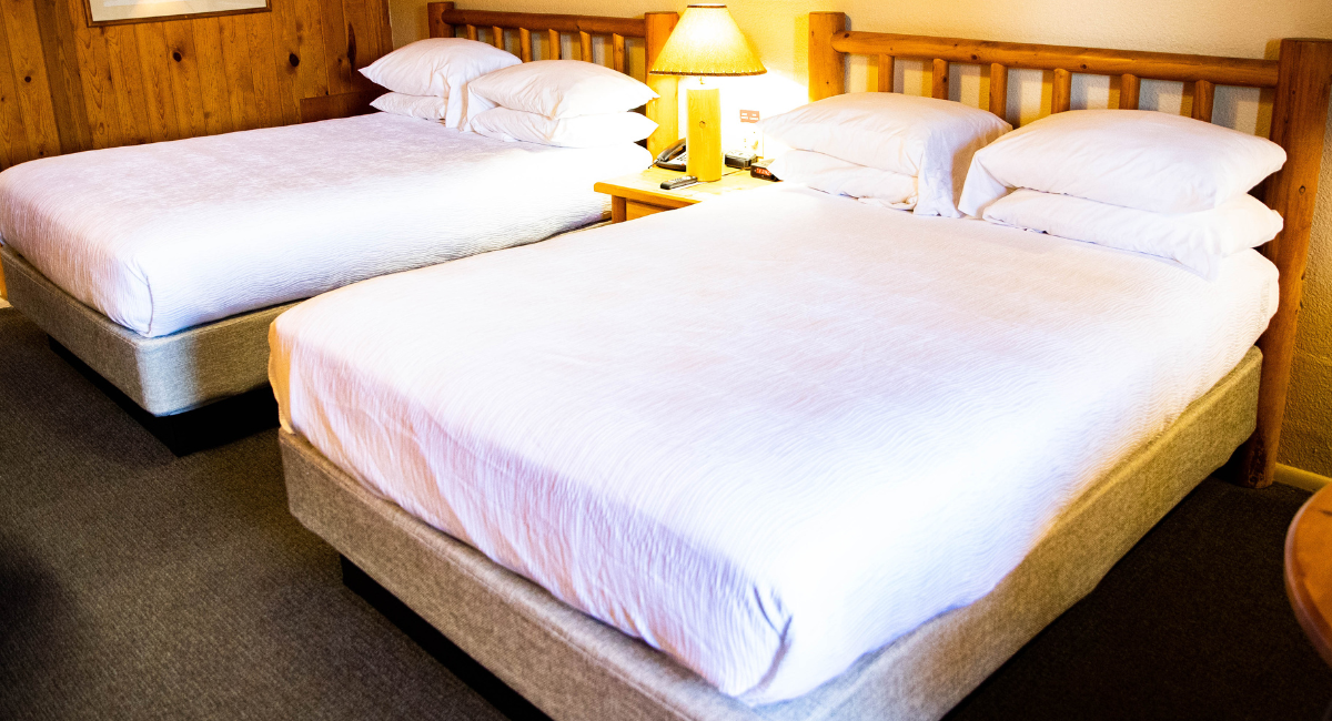 A hotel room with two beds and a lamp on a nightstand