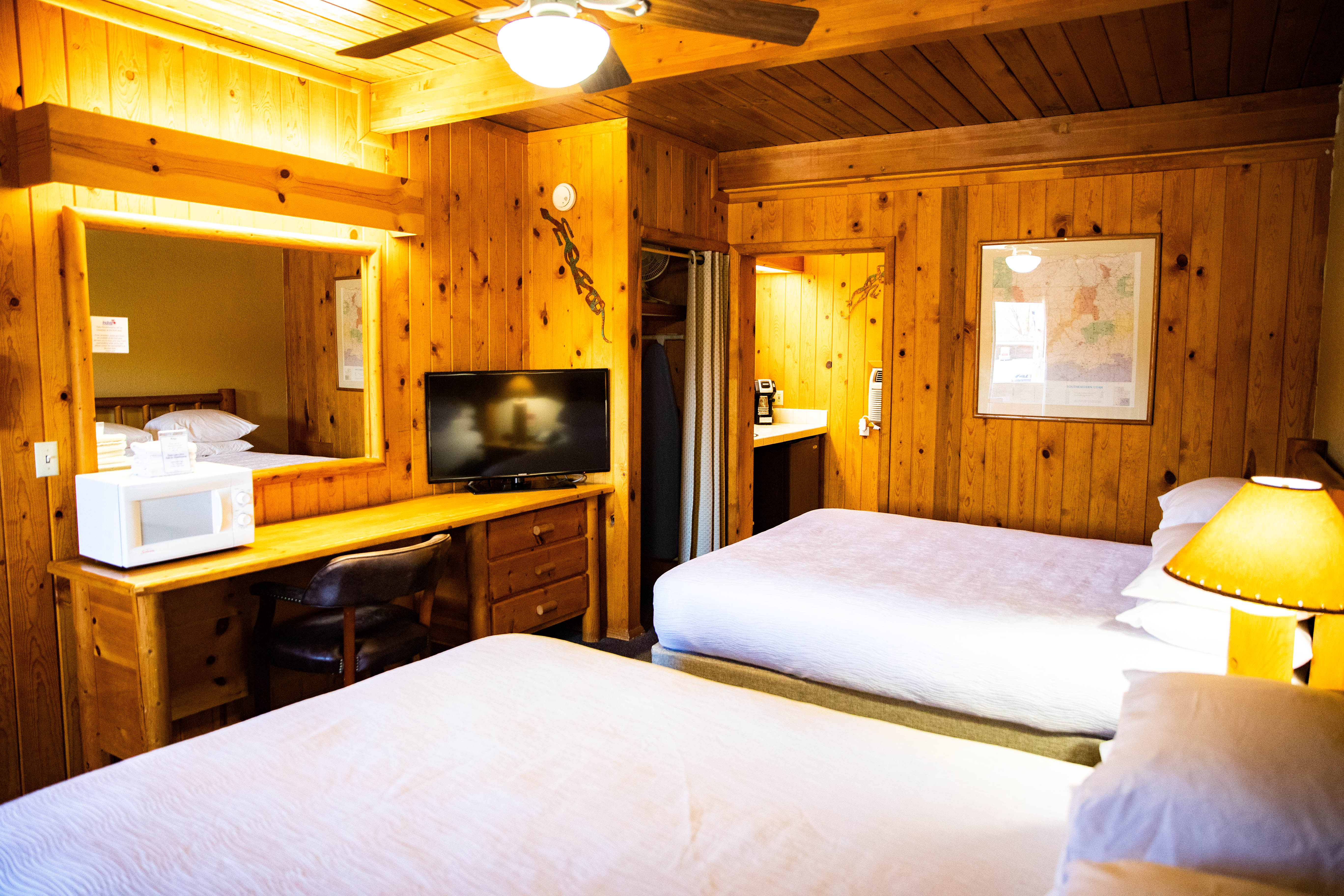 A hotel room with two queen beds, a desk, and a TV.