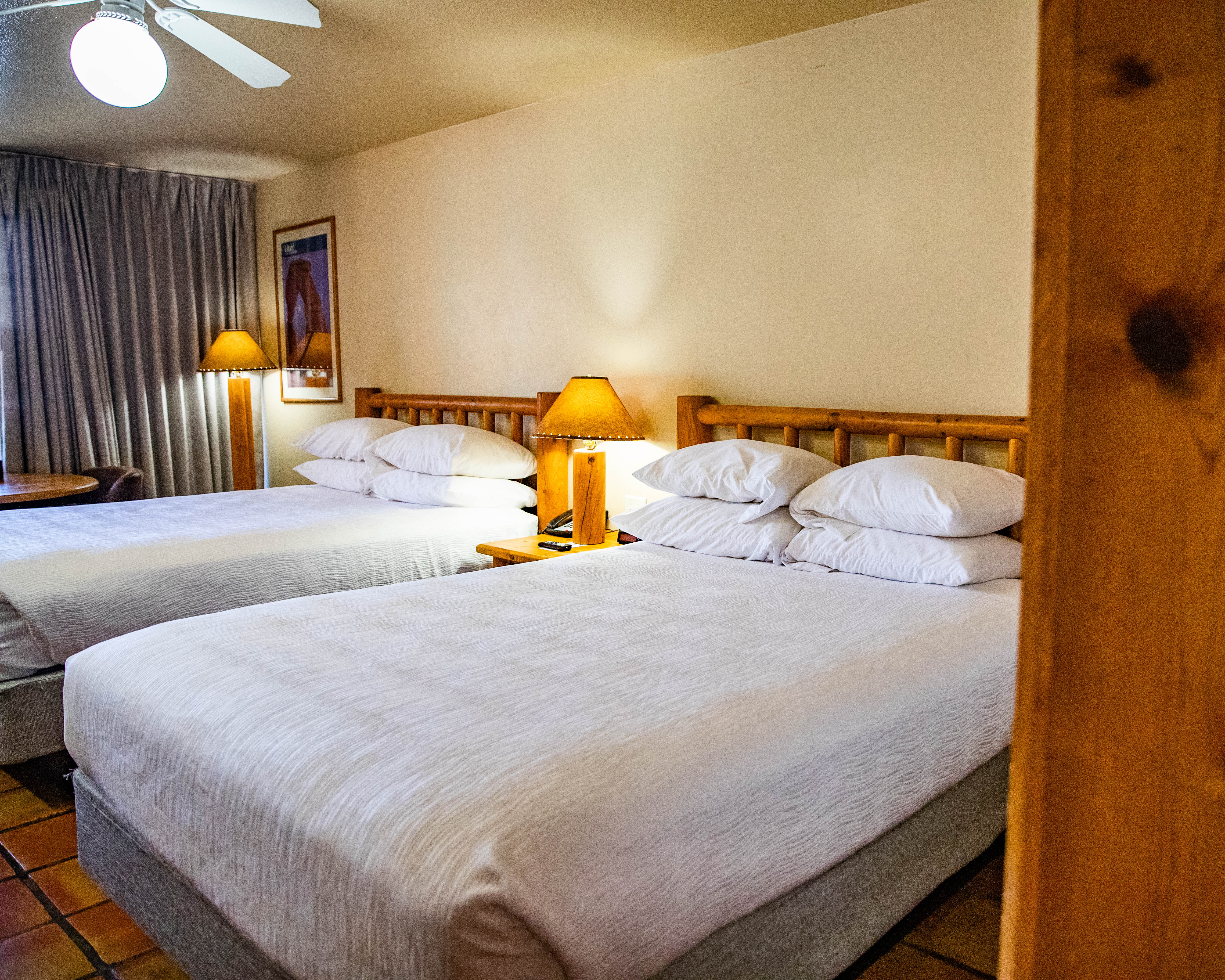 A hotel room with two double beds, wooden headboards, and lamps on nightstands