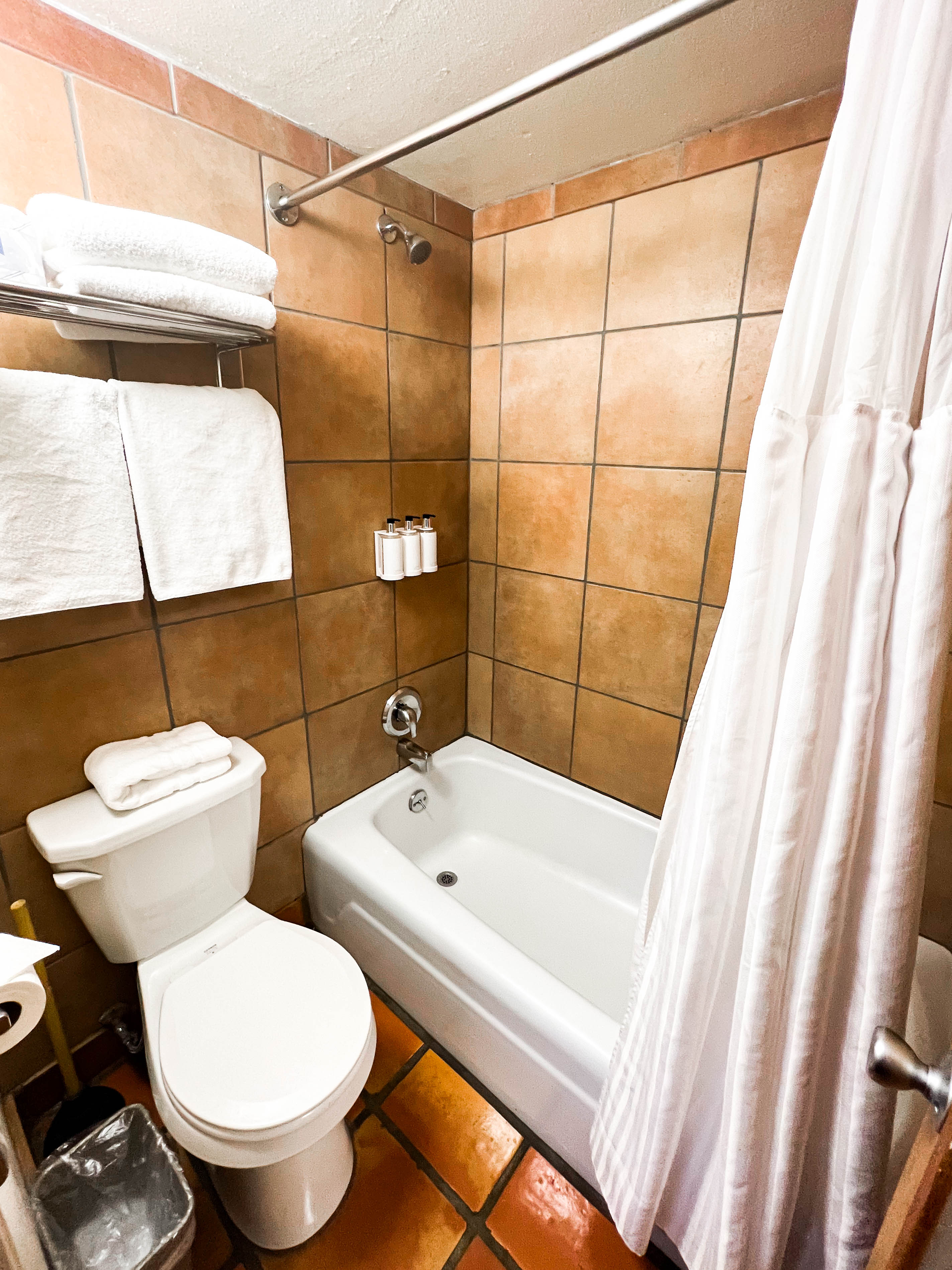 A bathroom with a toilet, bathtub, and tiled walls and floor.